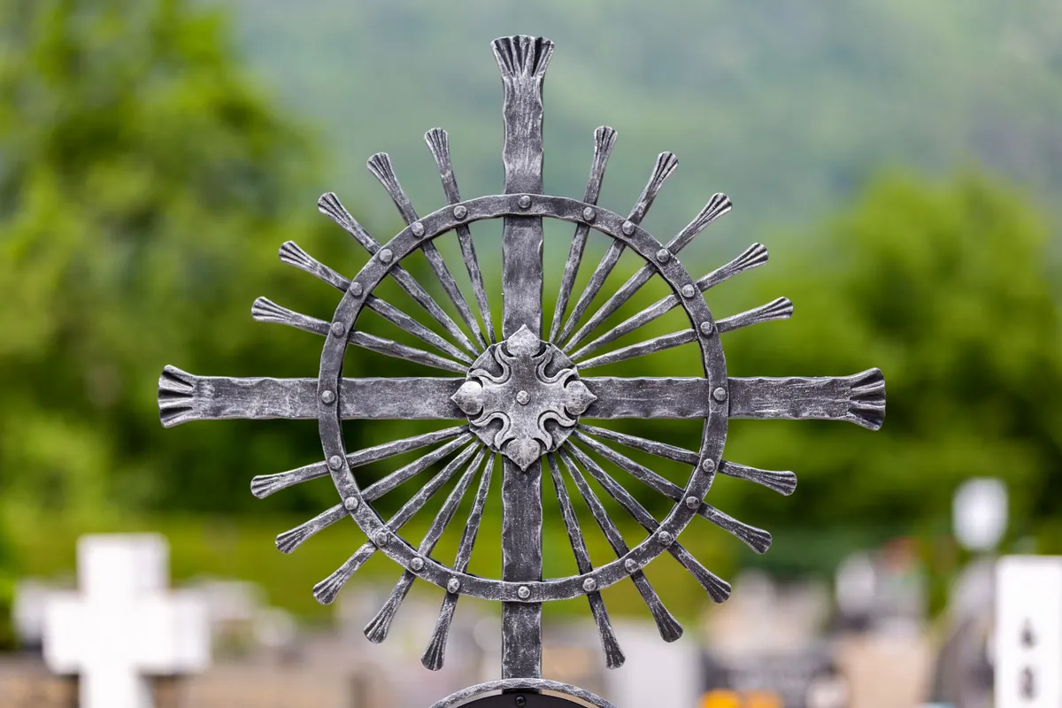 Strahlenkranz-Grabkreuz auf einem Friedhof am Alpenrand
