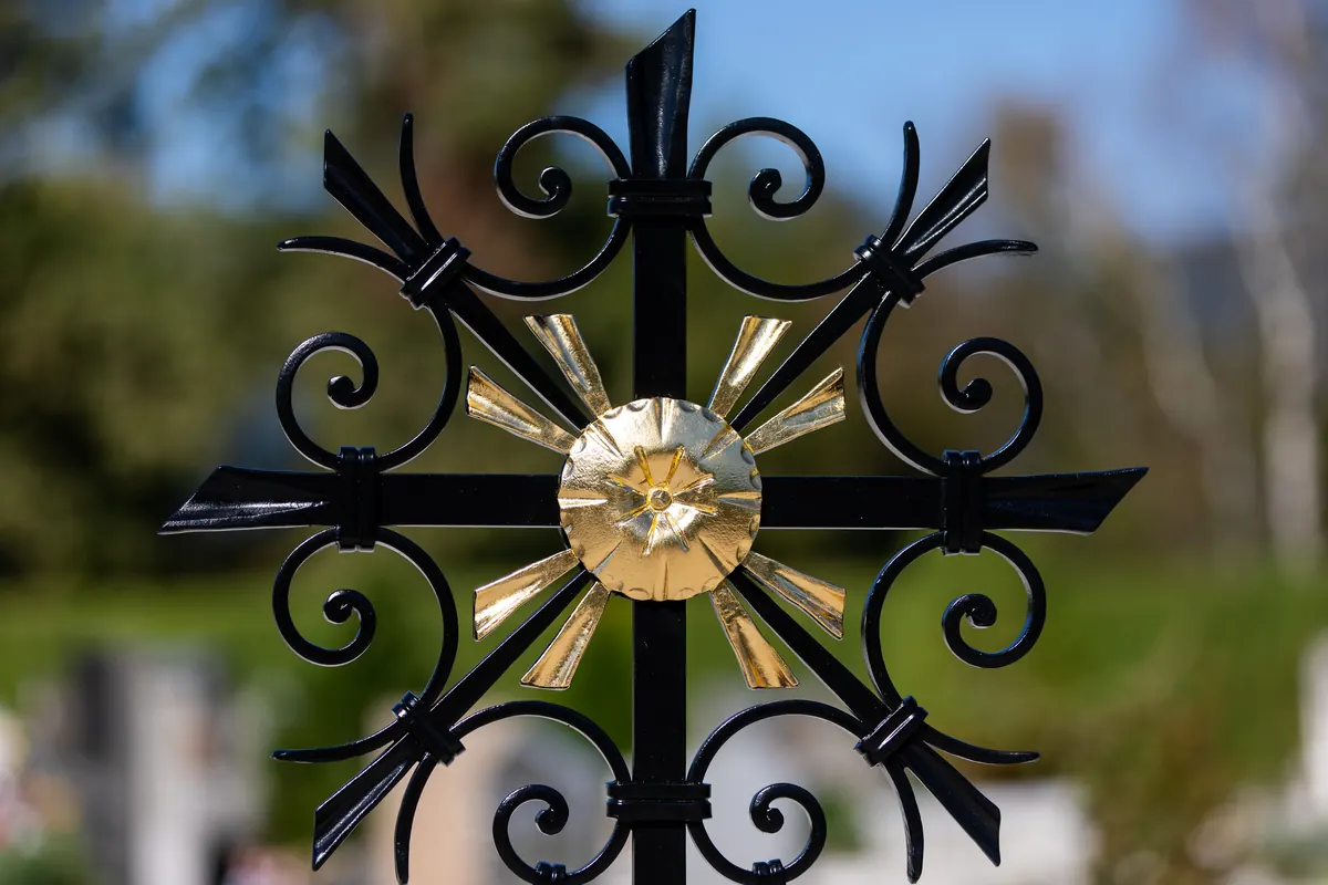 Schwarzes Schmiedekreuz mit vergoldeter Sonnenrosette, gefertigt in der Werkstatt der Grabkreuz Schmiede
